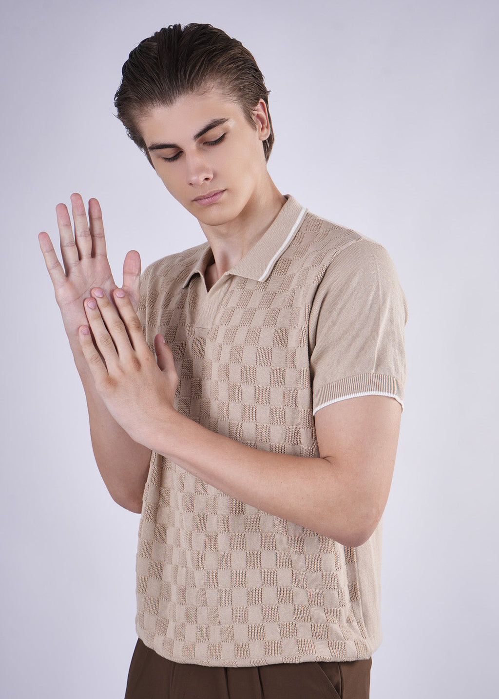 Person wearing a beige patterned shirt on a plain background