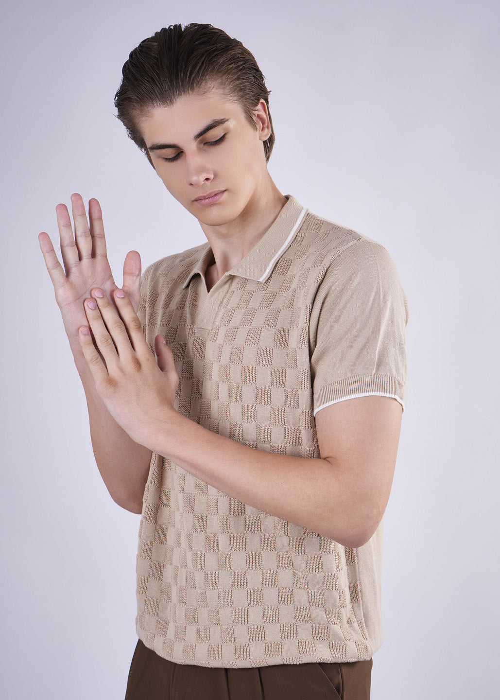 Person wearing a beige patterned shirt on a plain background