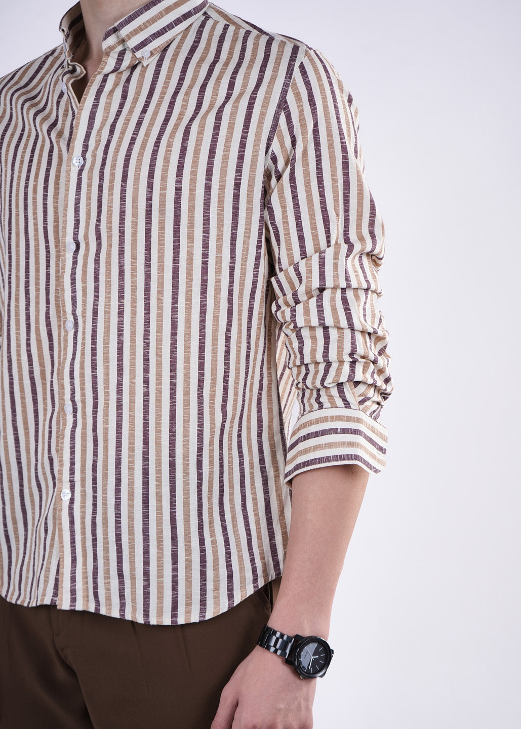 Person wearing a striped shirt with rolled-up sleeves on a white background