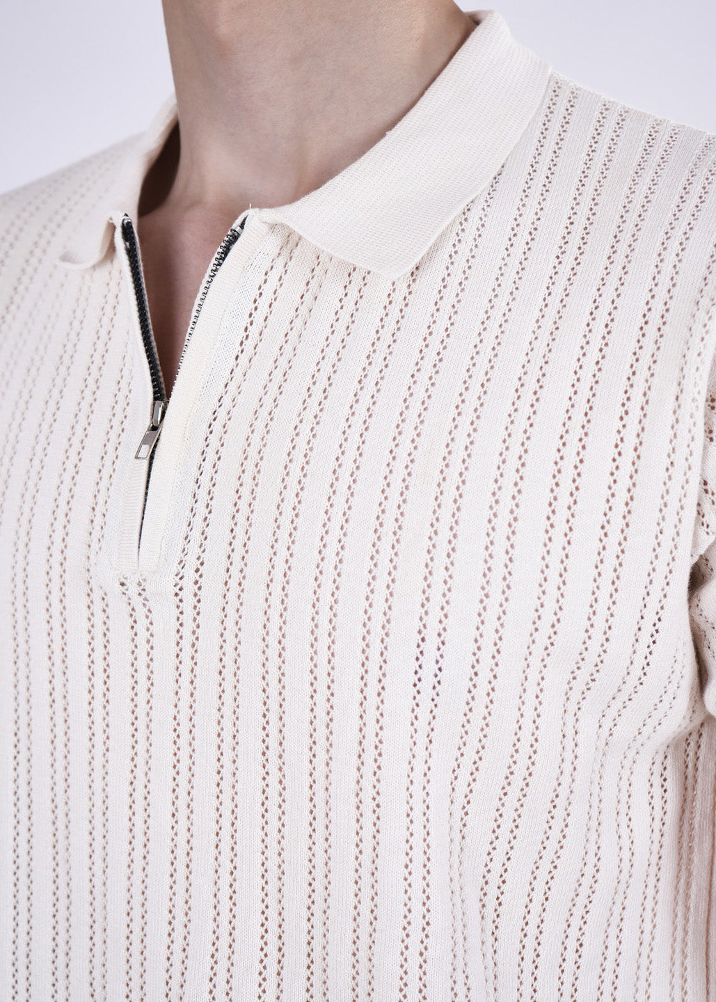 Close-up of a beige knit sweater with a zipper on a plain background