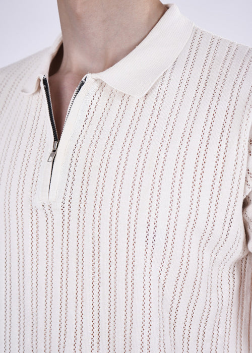 Close-up of a beige knit sweater with a zipper on a plain background