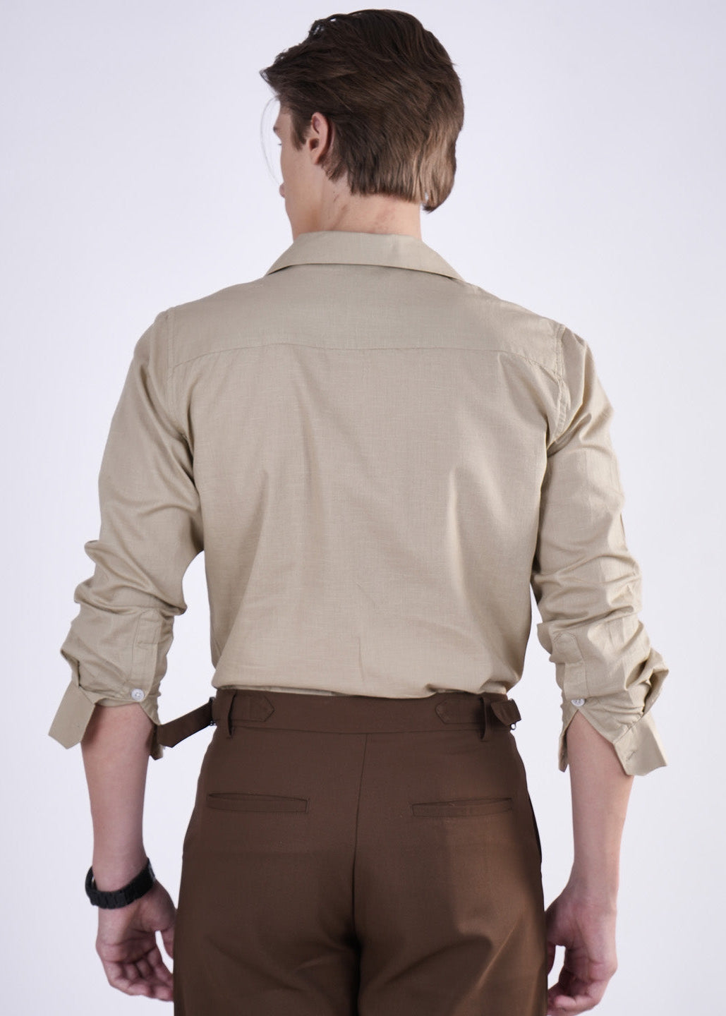 Man wearing a beige shirt and brown pants on a white background