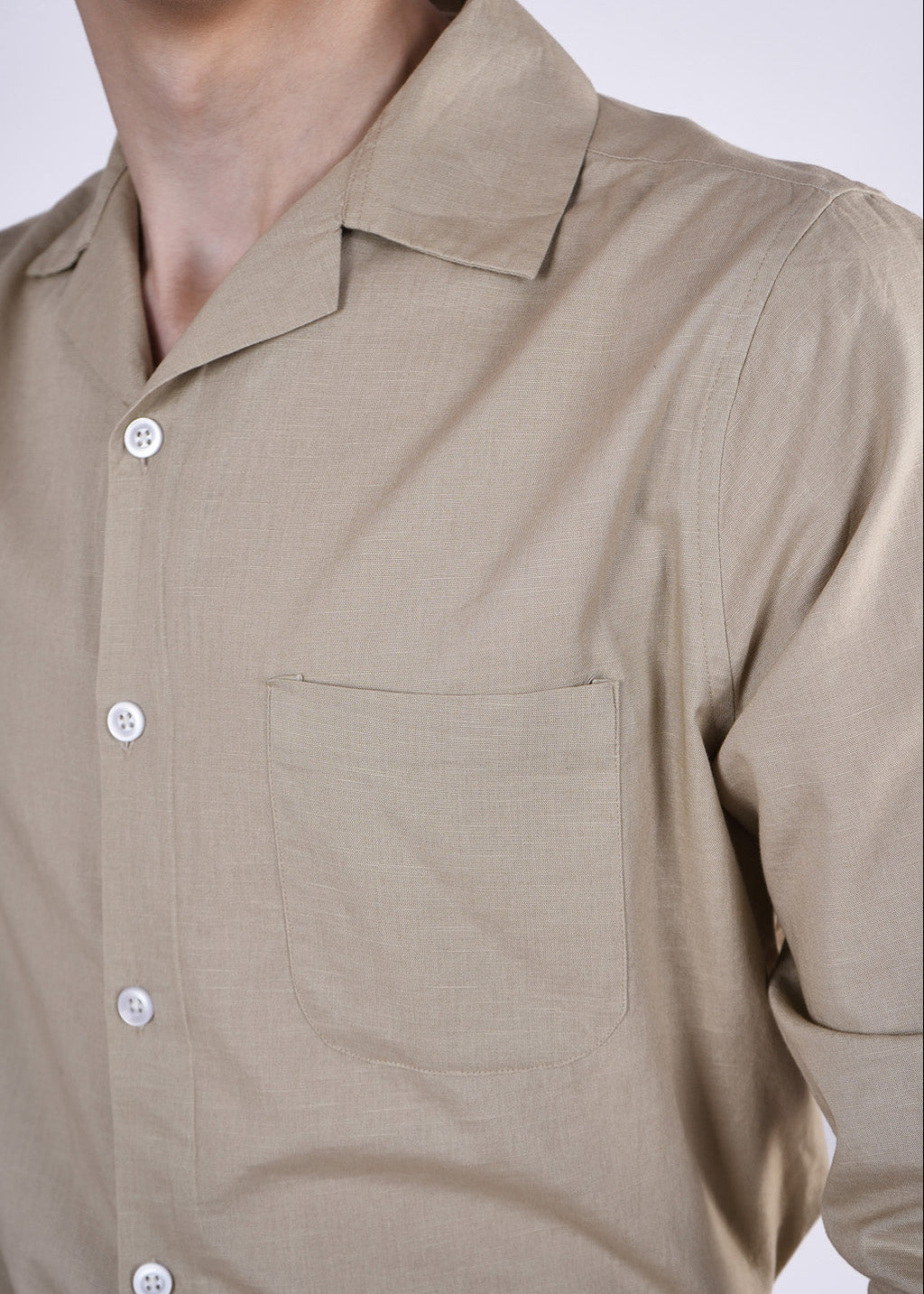 Close-up of a beige button-up shirt with a pocket on a white background