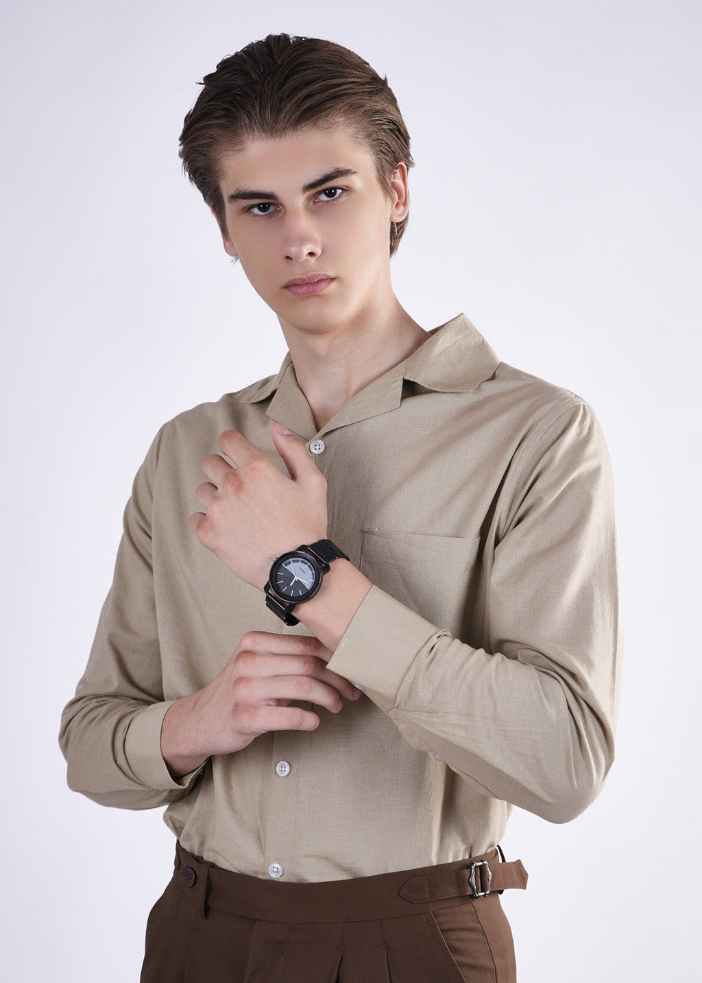 Man wearing a beige shirt and brown pants on a white background
