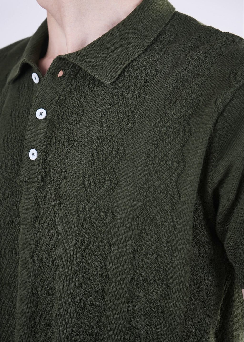 Close-up of a green patterned shirt with buttons on a plain background