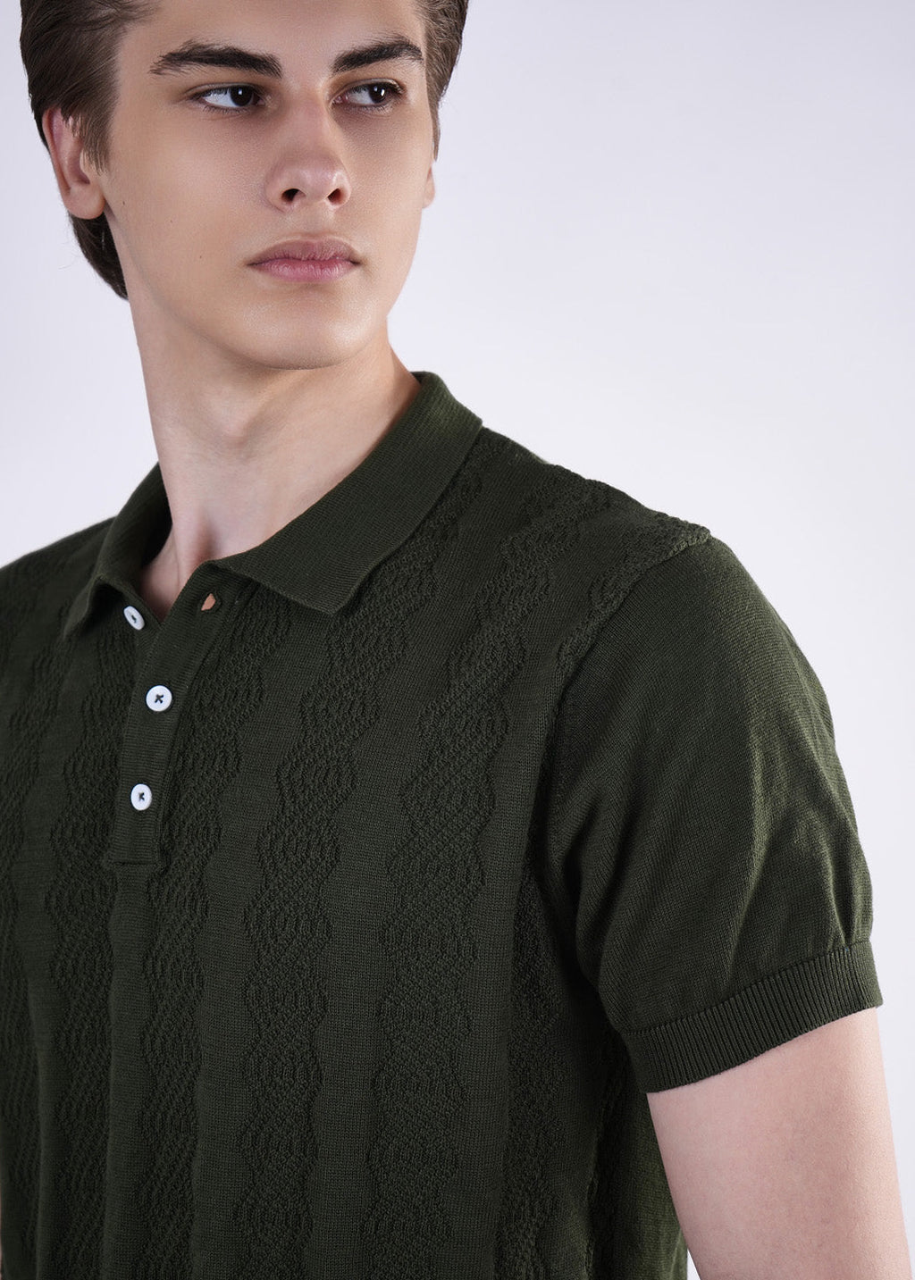 Man wearing a dark green knitted polo shirt against a white background
