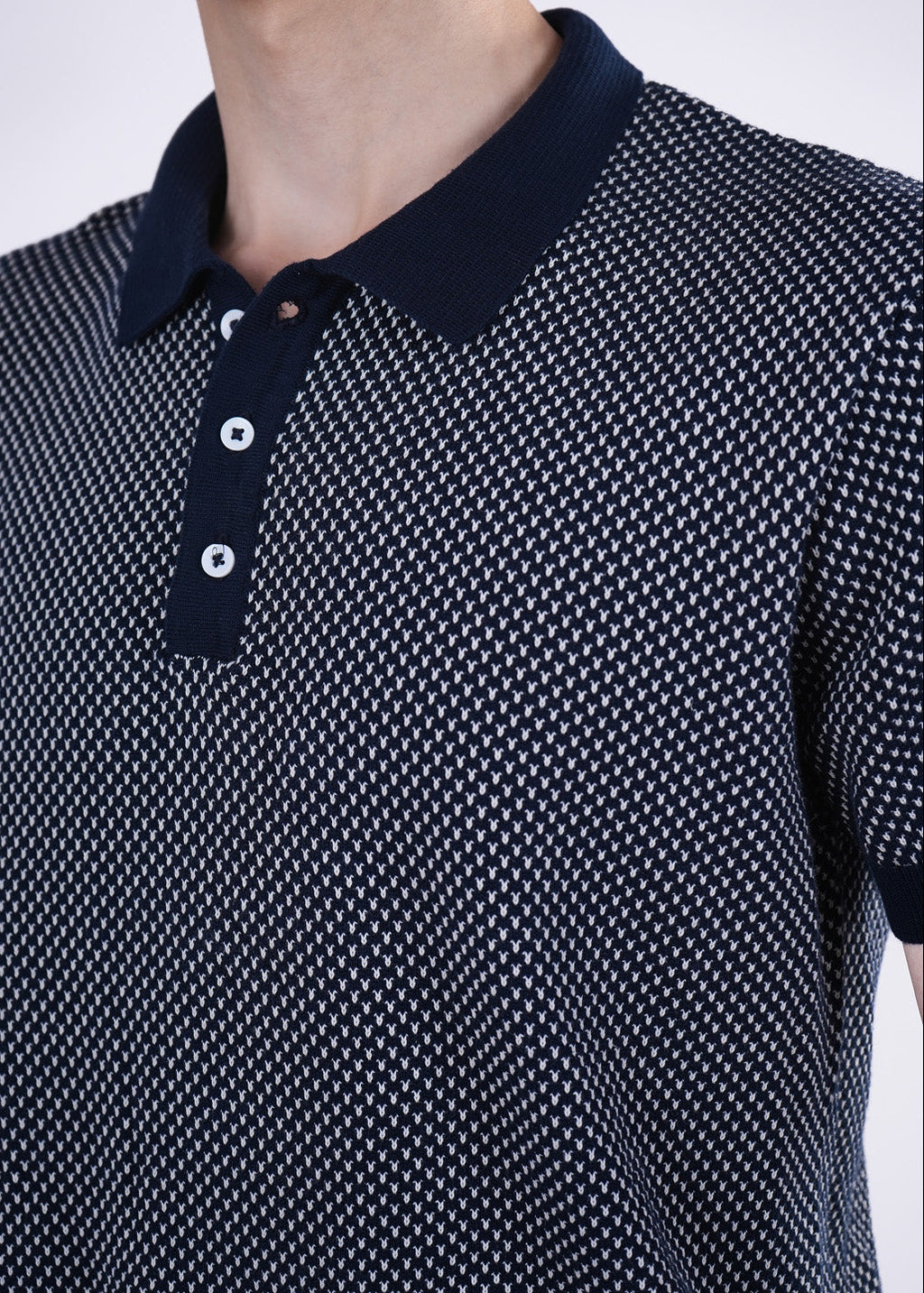 Navy blue and white patterned polo shirt on a plain background