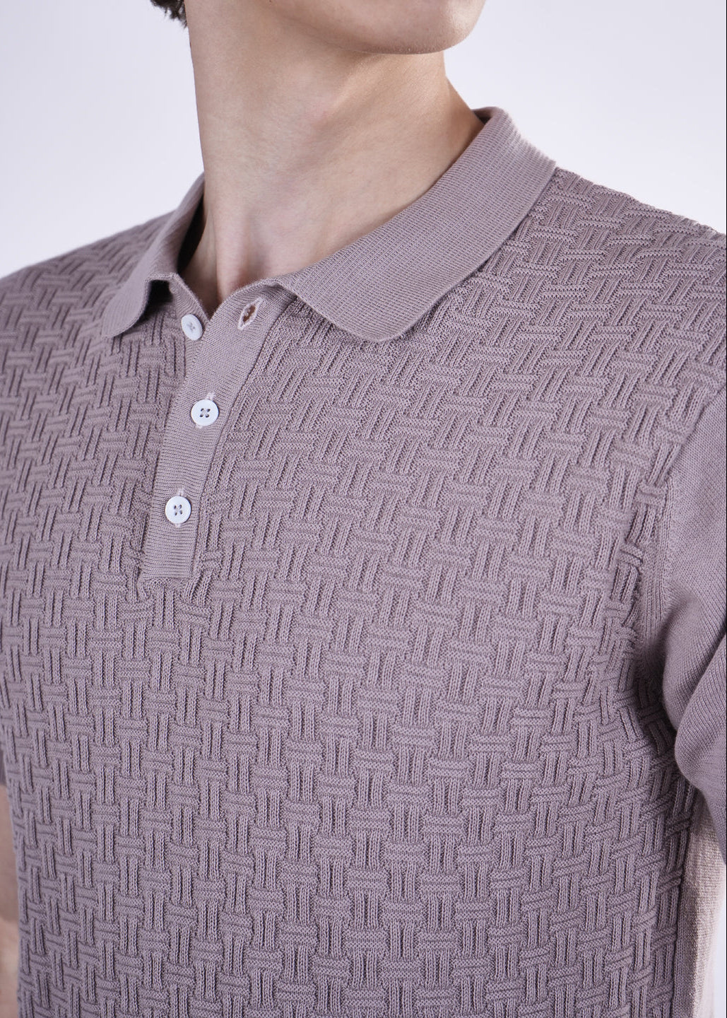 Close-up of a person wearing a patterned purple polo shirt against a neutral background