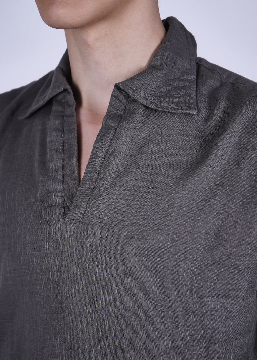 Close-up of a person wearing a dark gray shirt with a collar.