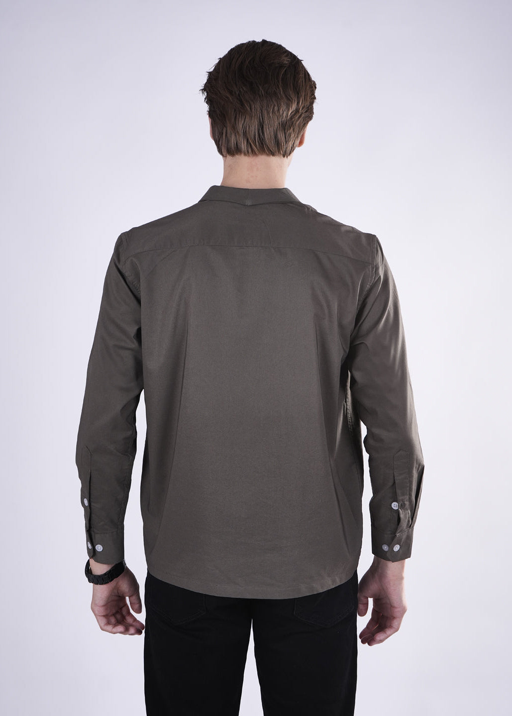 Man wearing a gray shirt with rolled-up sleeves on a white background