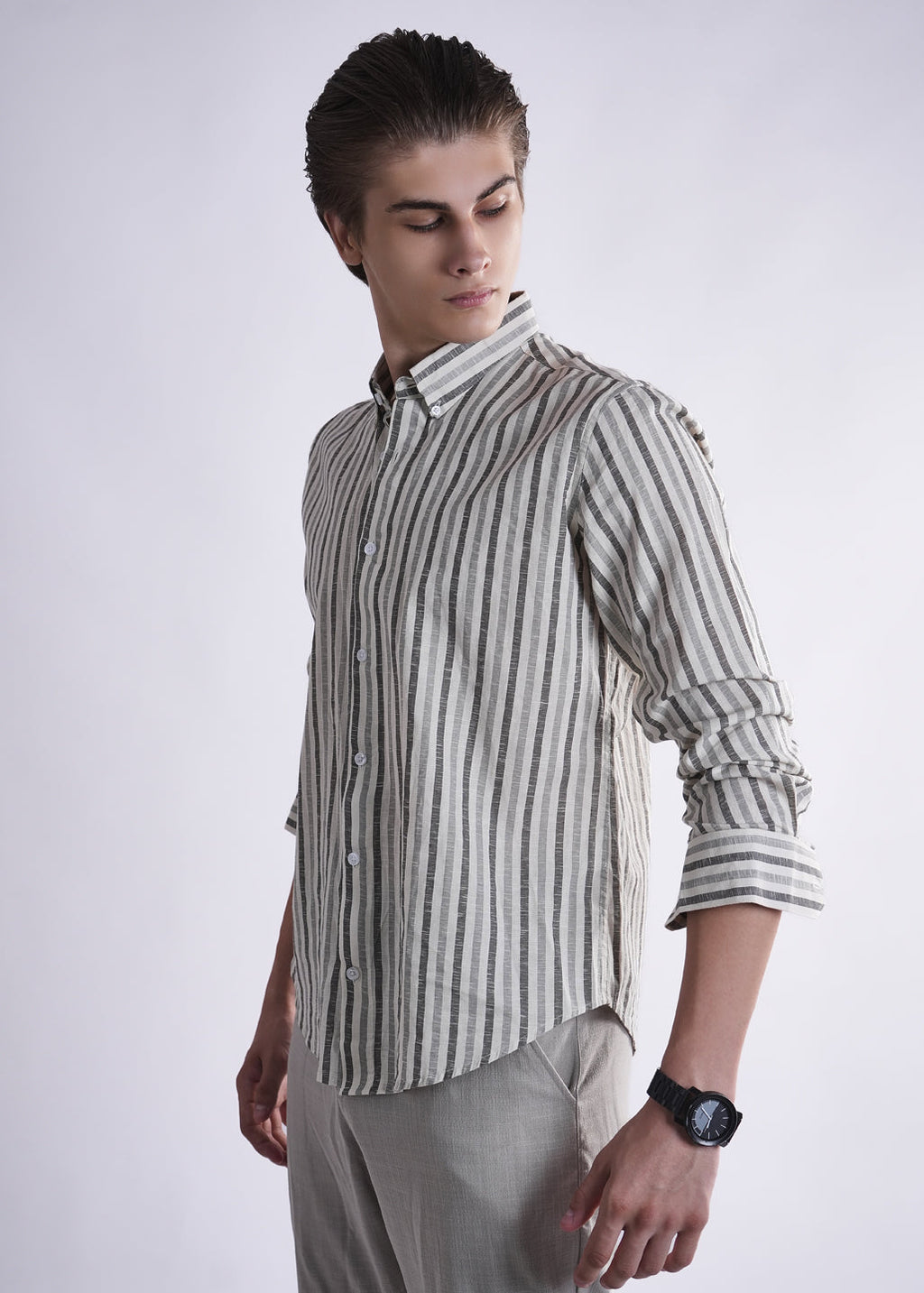 Man wearing a striped shirt and light gray pants on a white background