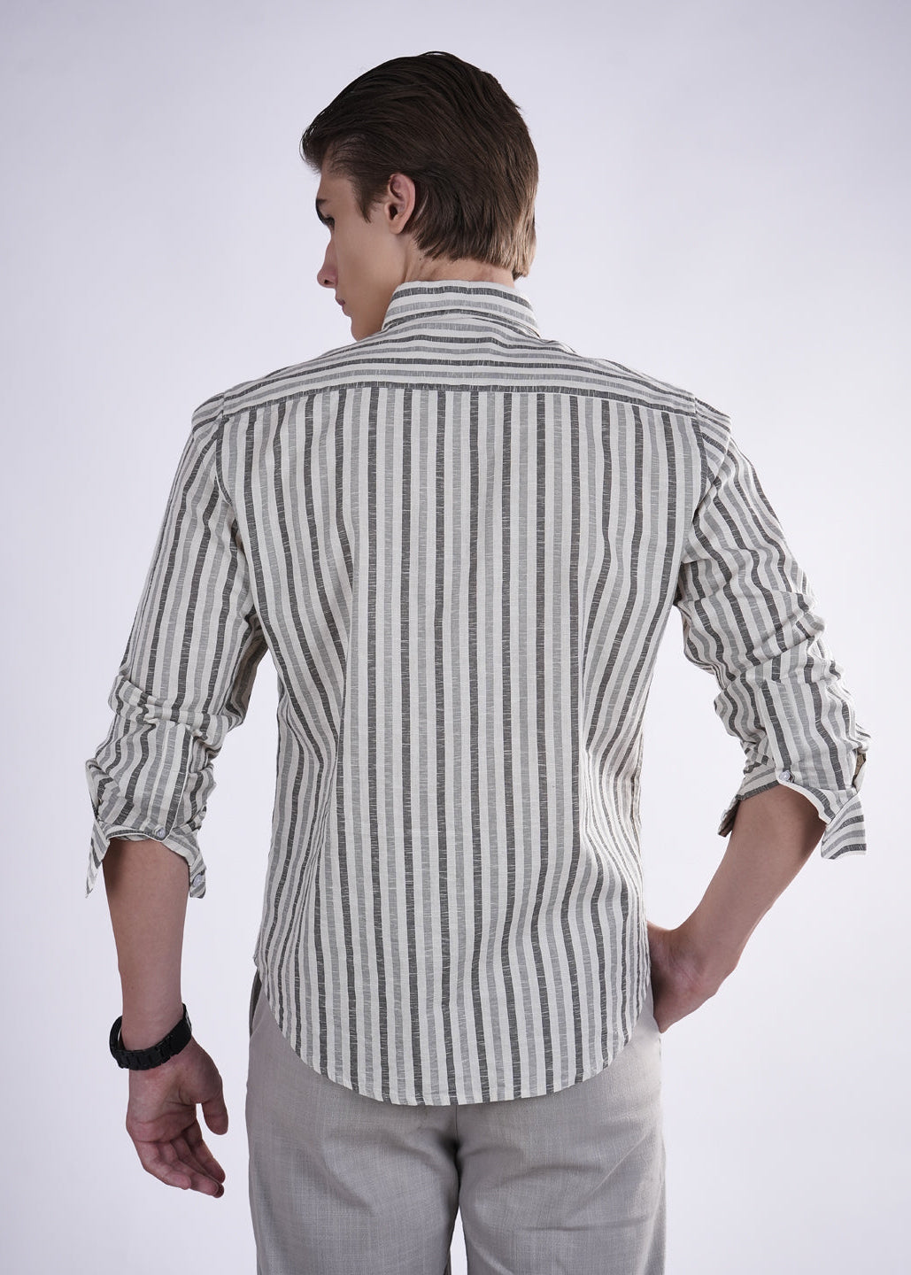 Man wearing a striped shirt and light pants on a white background