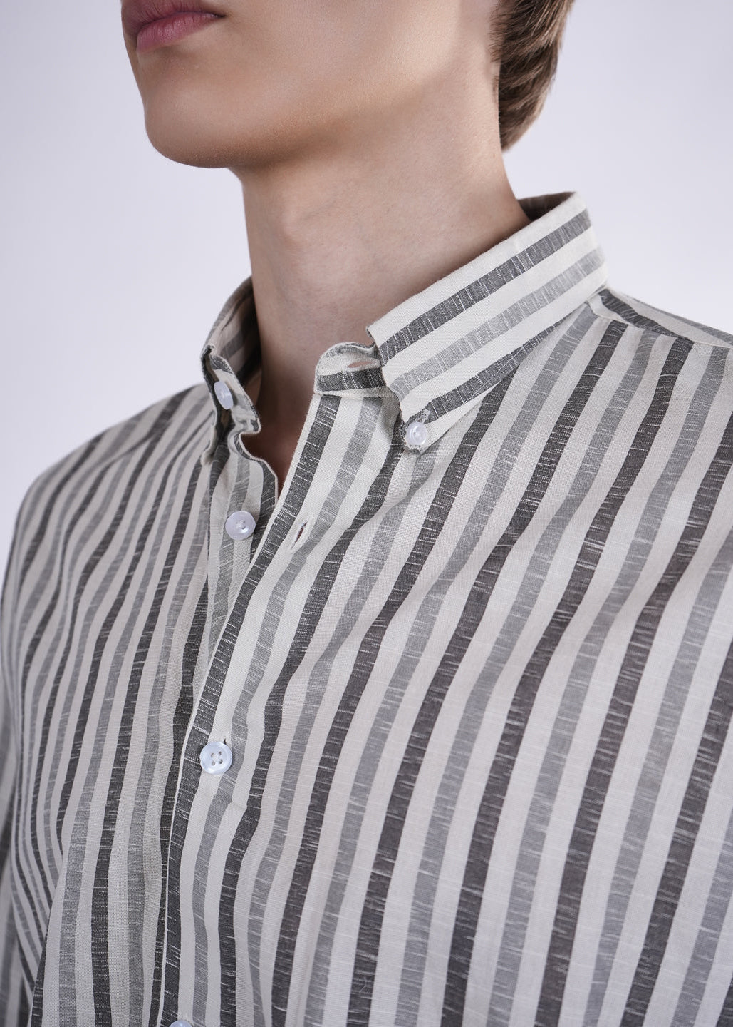 Close-up of a person wearing a striped shirt with a plain background