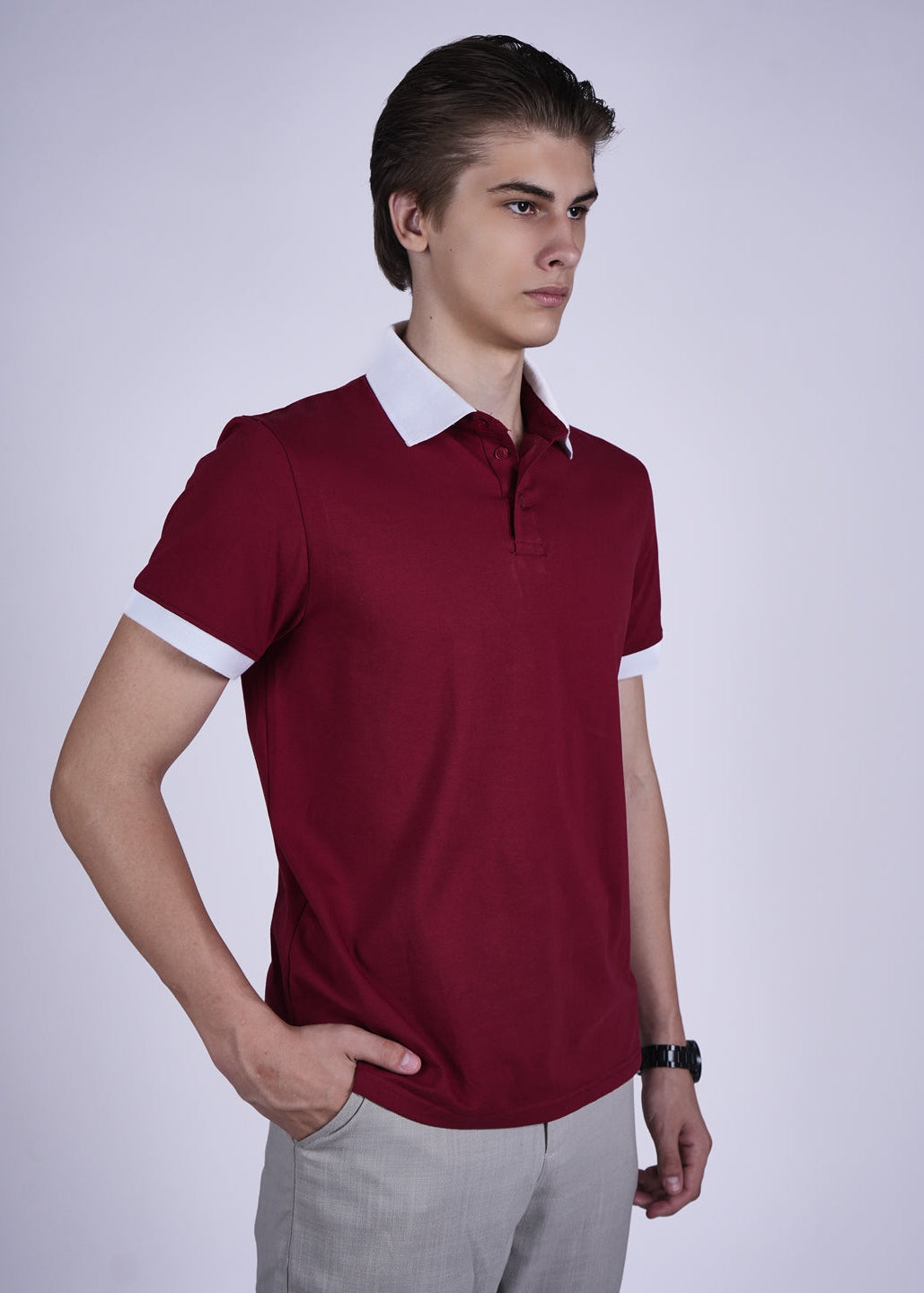 Man wearing a maroon polo shirt with white collar against a plain background