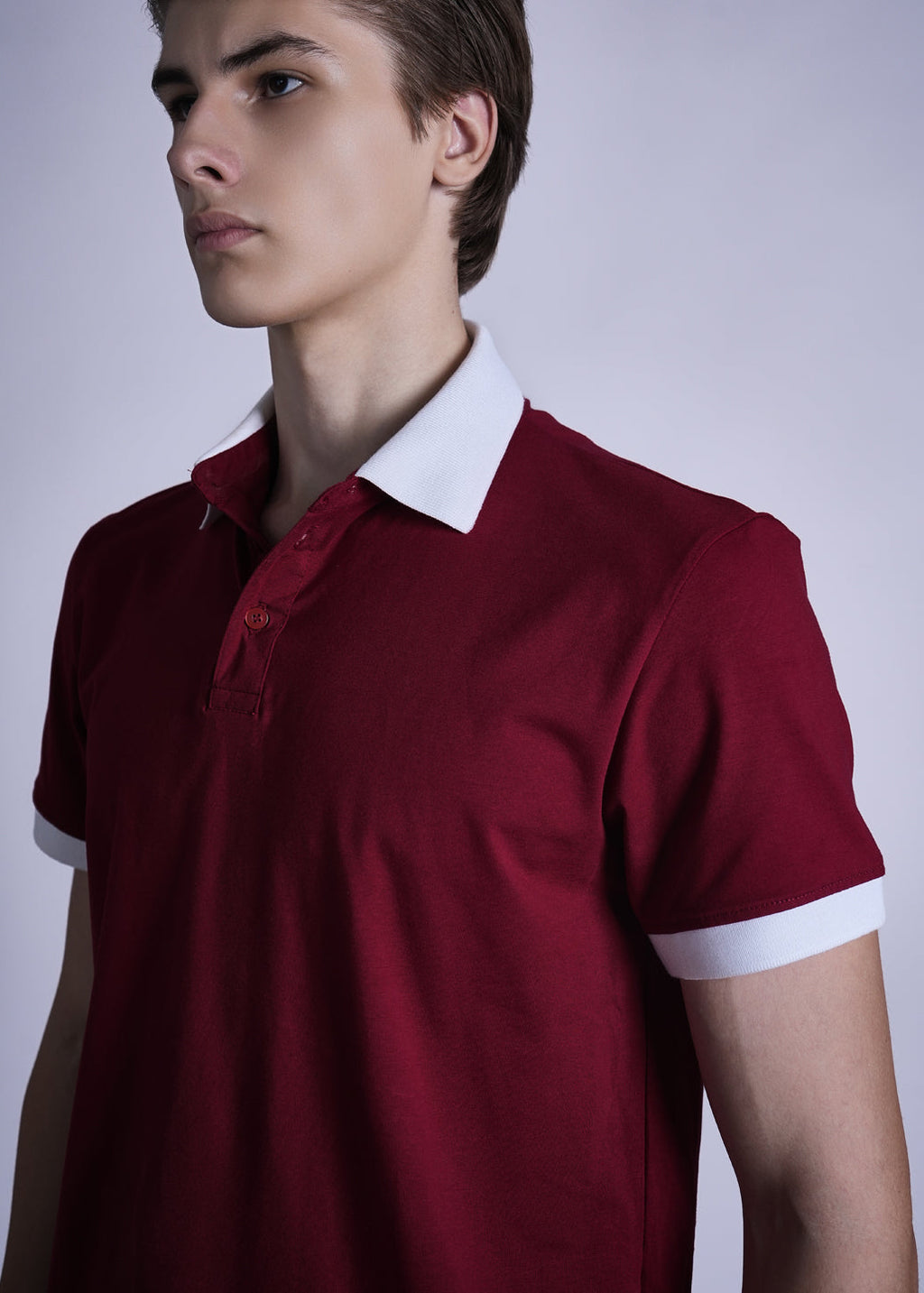 Man wearing a red polo shirt with white collar and cuffs against a plain background