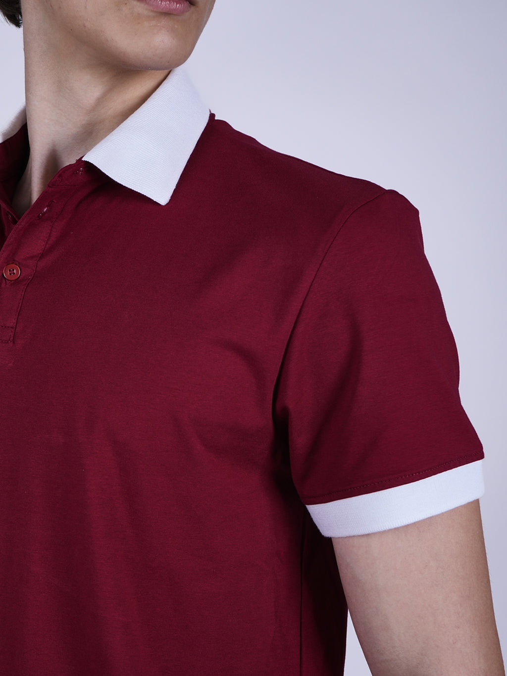 Maroon polo shirt with white collar and cuffs on a plain background