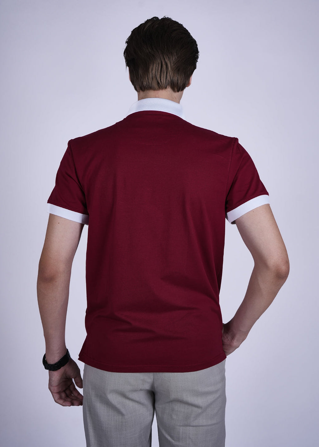 Person wearing a maroon polo shirt with white trim on a plain background