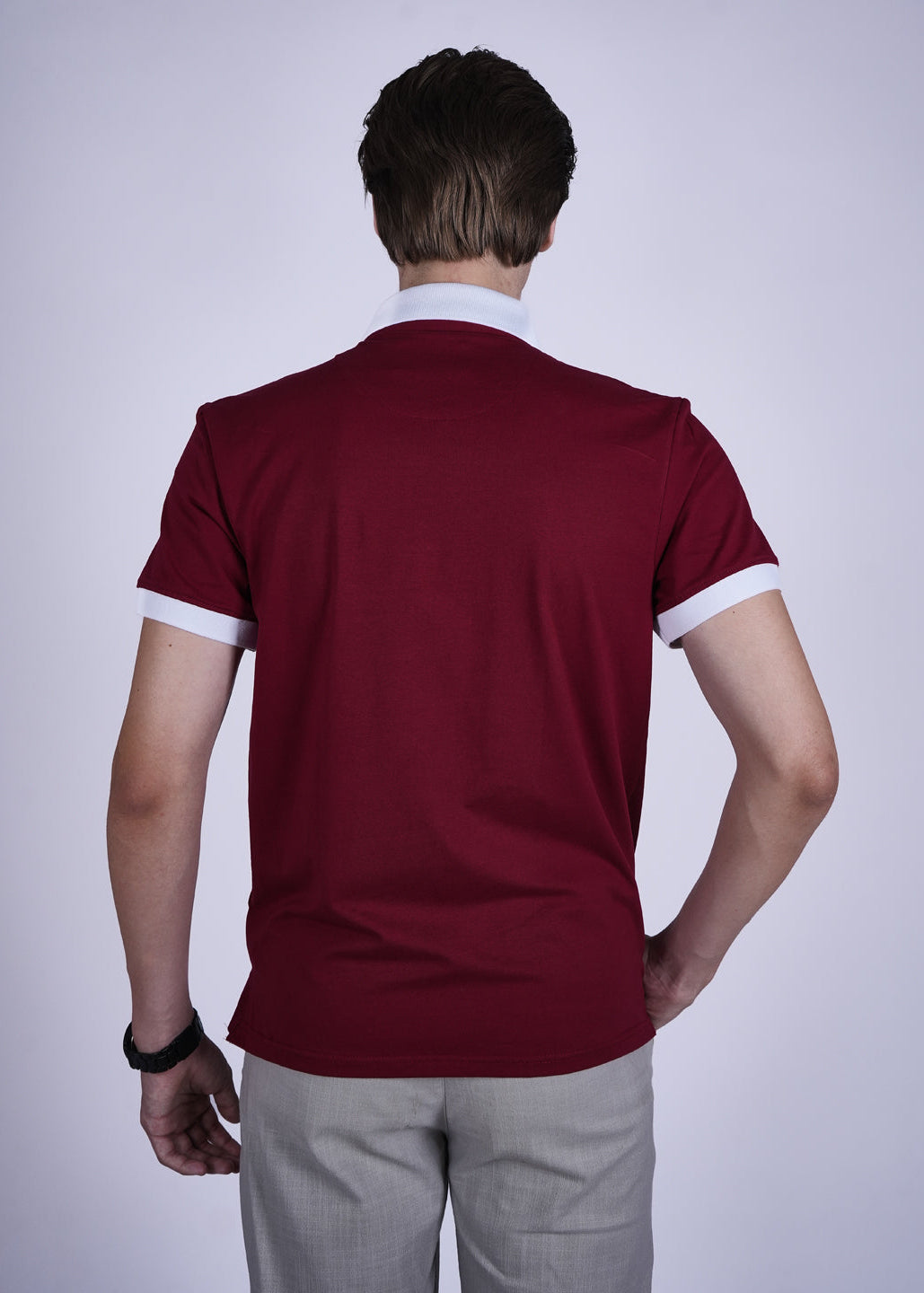 Person wearing a maroon polo shirt with white trim on a plain background
