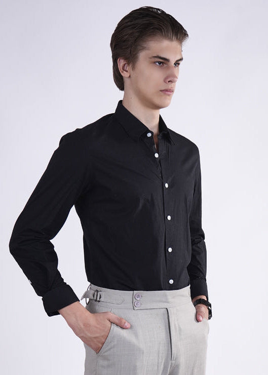 Man wearing a black shirt and gray pants on a white background