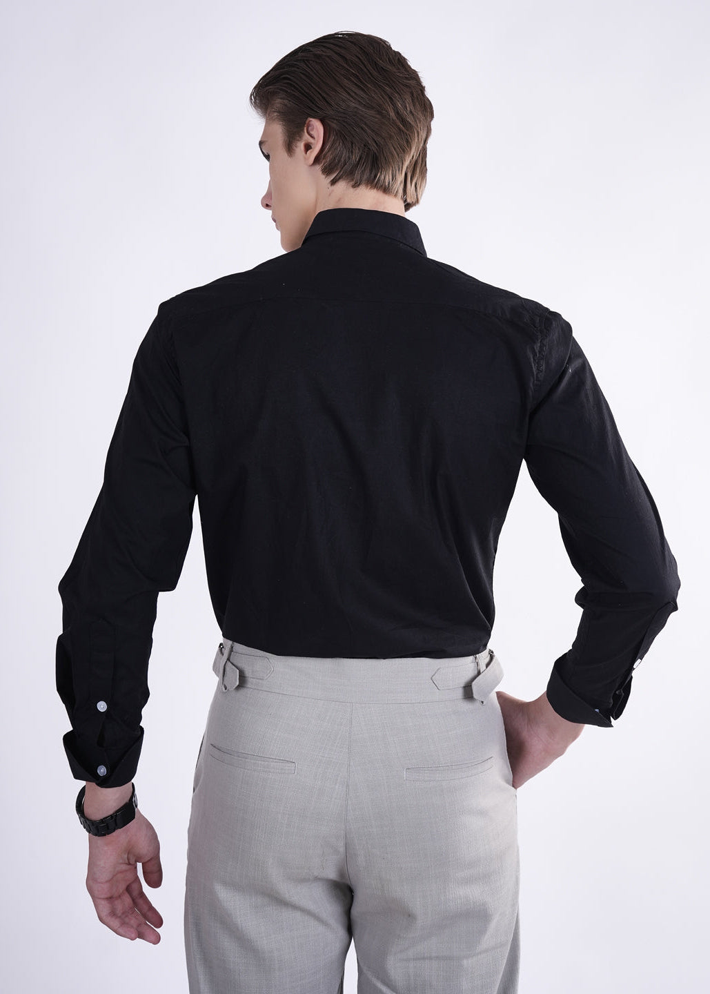 Man wearing a black shirt and gray pants on a white background