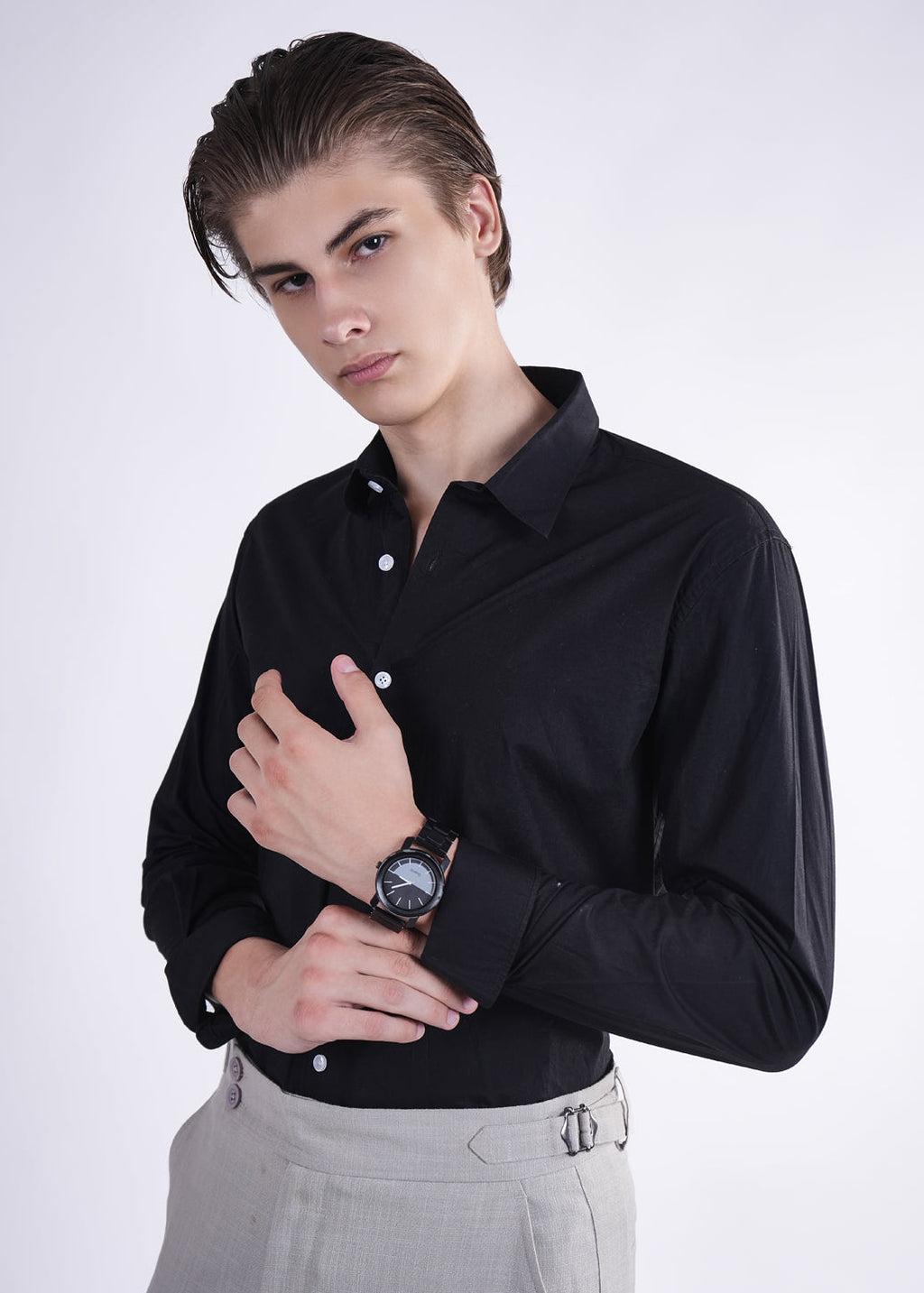 Man wearing a black dress shirt and gray pants on a white background