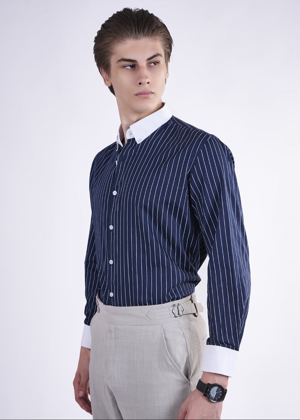 Man wearing a navy striped shirt with a white collar on a plain background