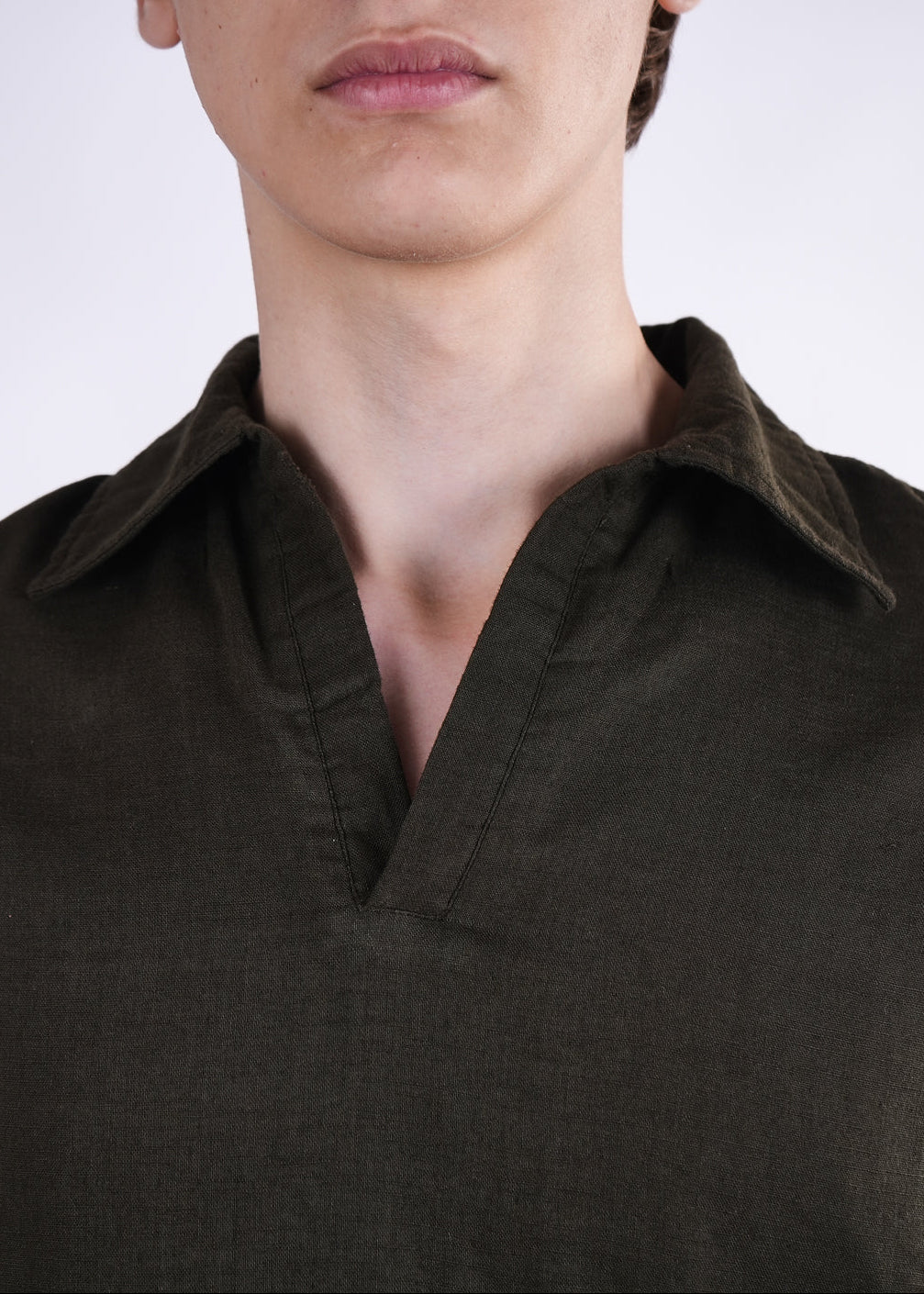 Close-up of a person wearing a dark green shirt against a white background