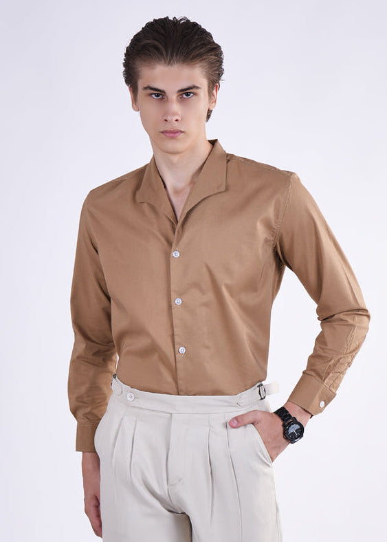 Man wearing a brown shirt and beige pants on a white background