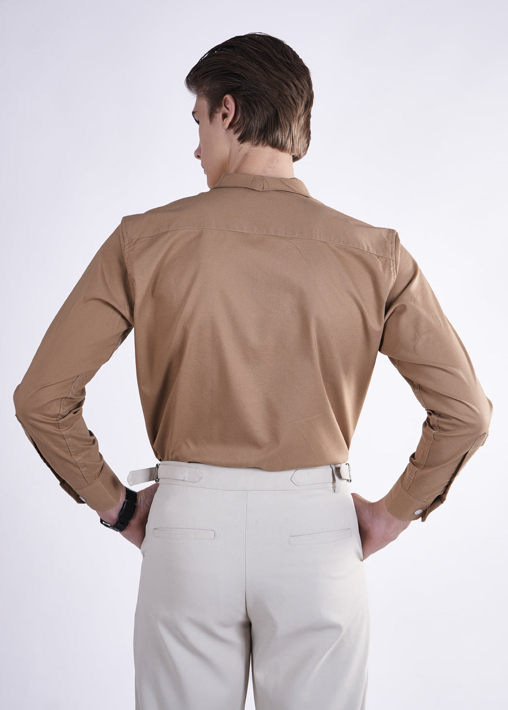 Person wearing a beige shirt and light-colored pants on a white background