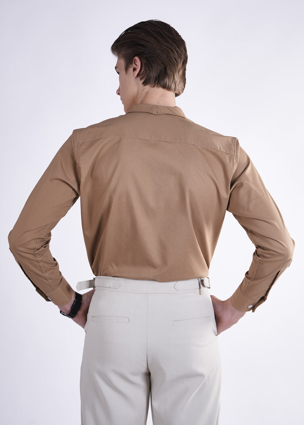 Person wearing a beige shirt and light-colored pants on a white background