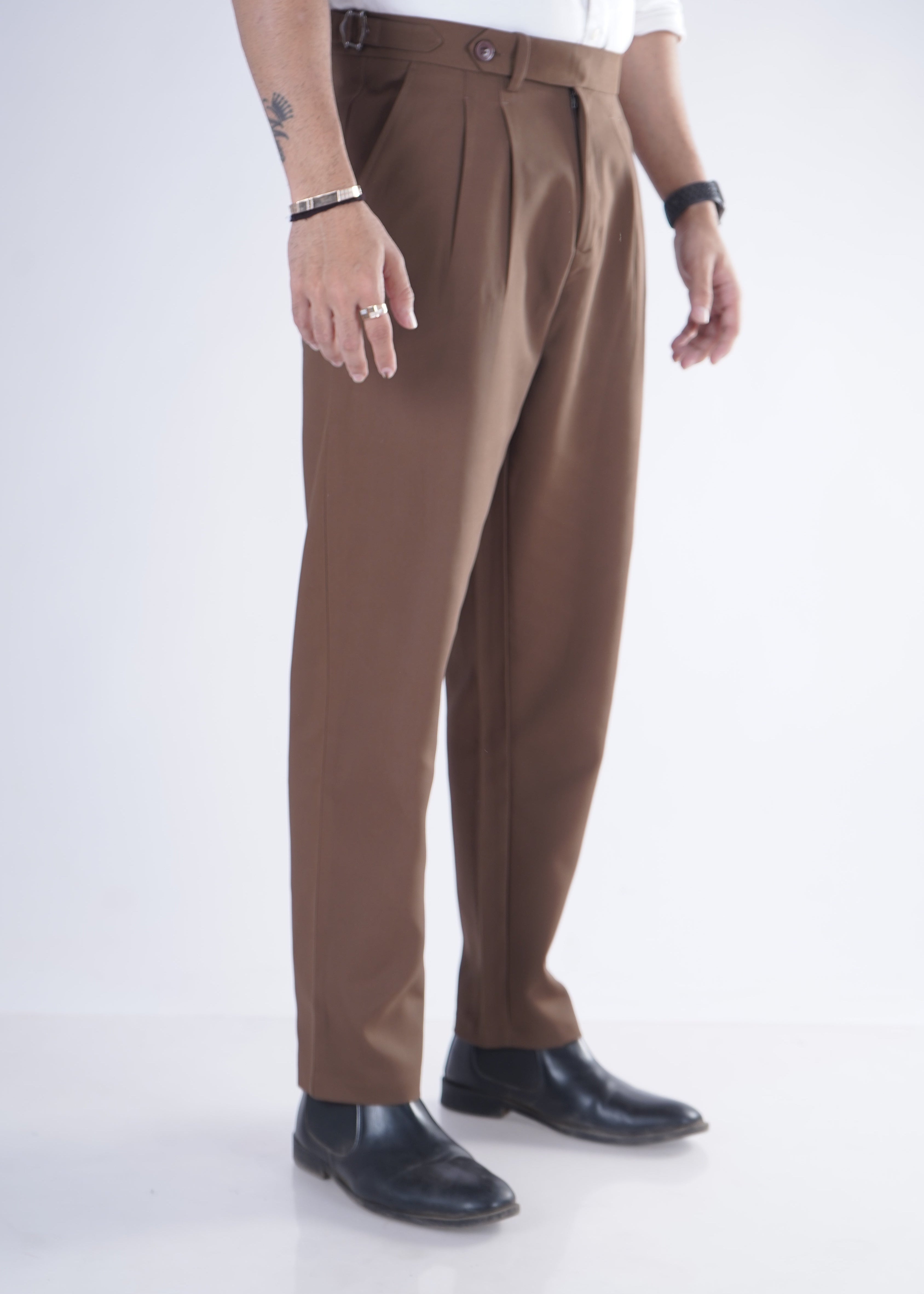 Person wearing brown pants and black shoes on a white background