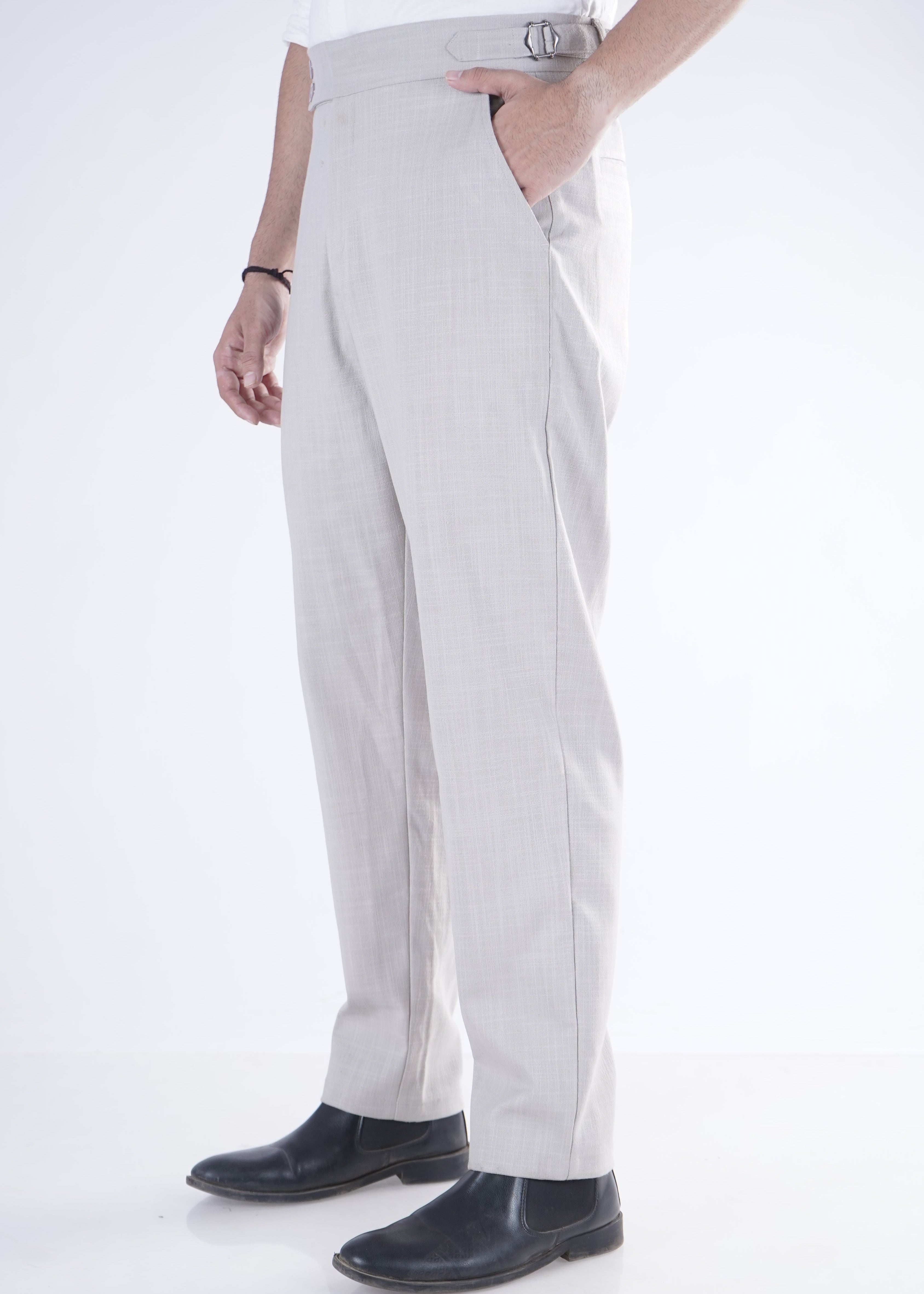 Person wearing light gray pants and black shoes on a white background