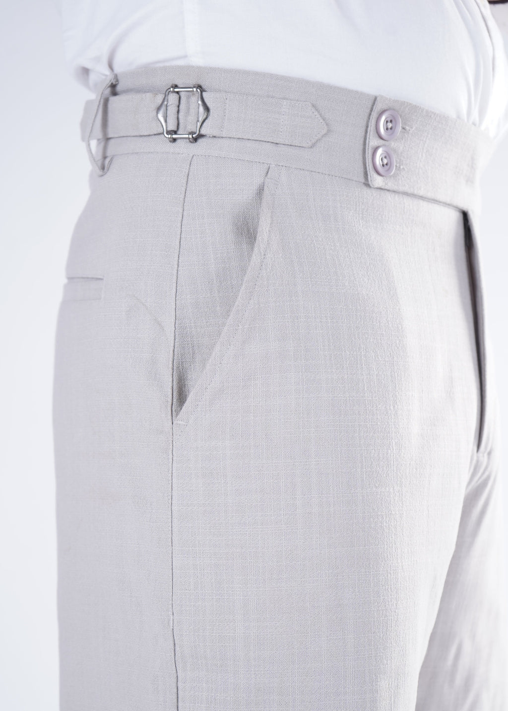 Close-up of light gray pants with a belt and buttons on a white background