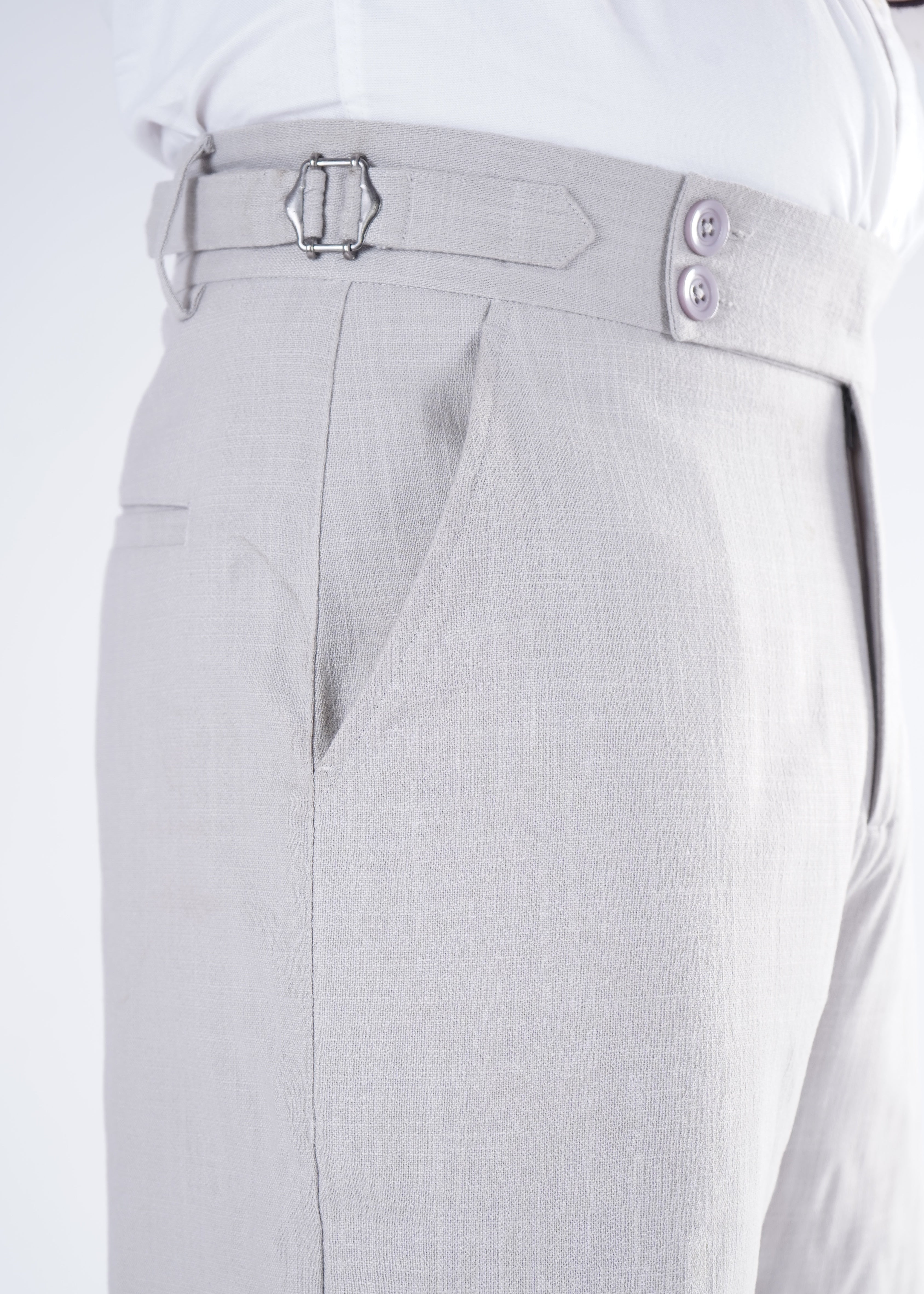 Close-up of light gray pants with a belt and buttons on a white background