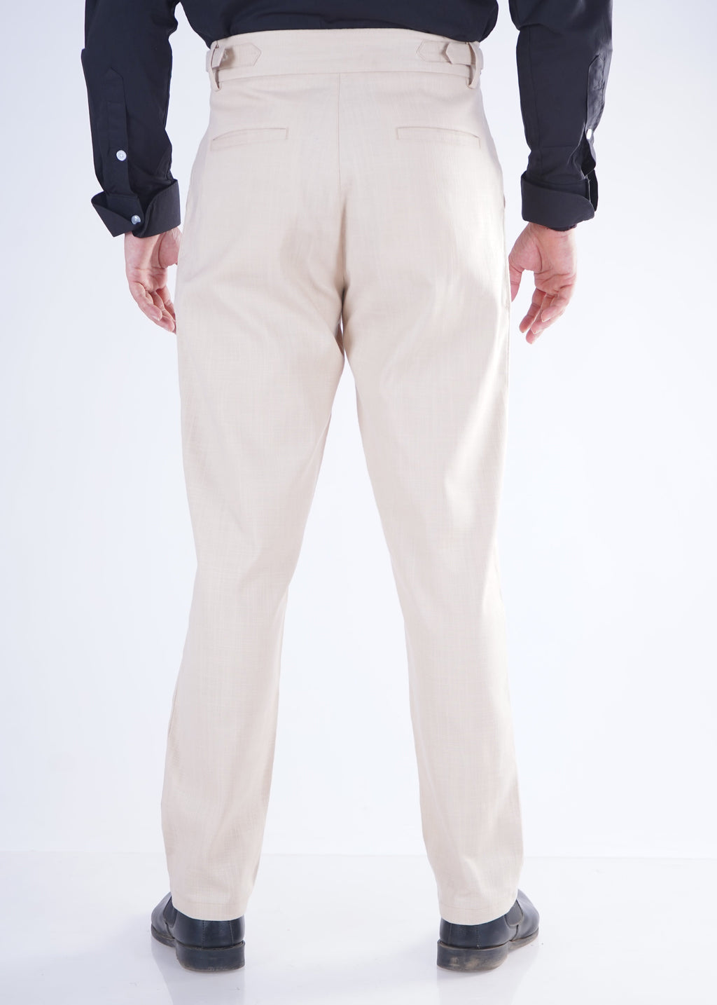 Person wearing beige pants and black shoes on a white background