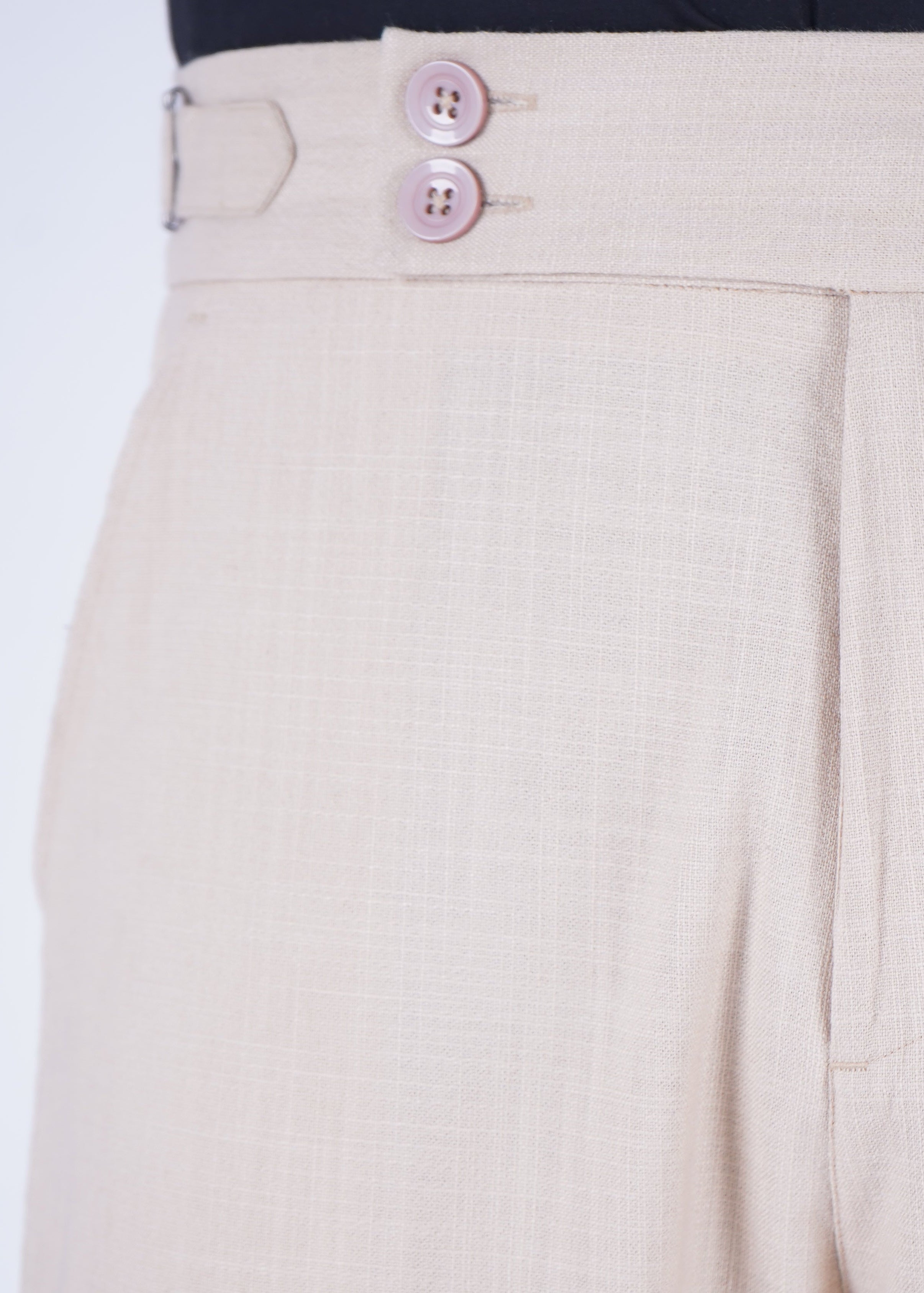 Beige pants with a button detail on a white background