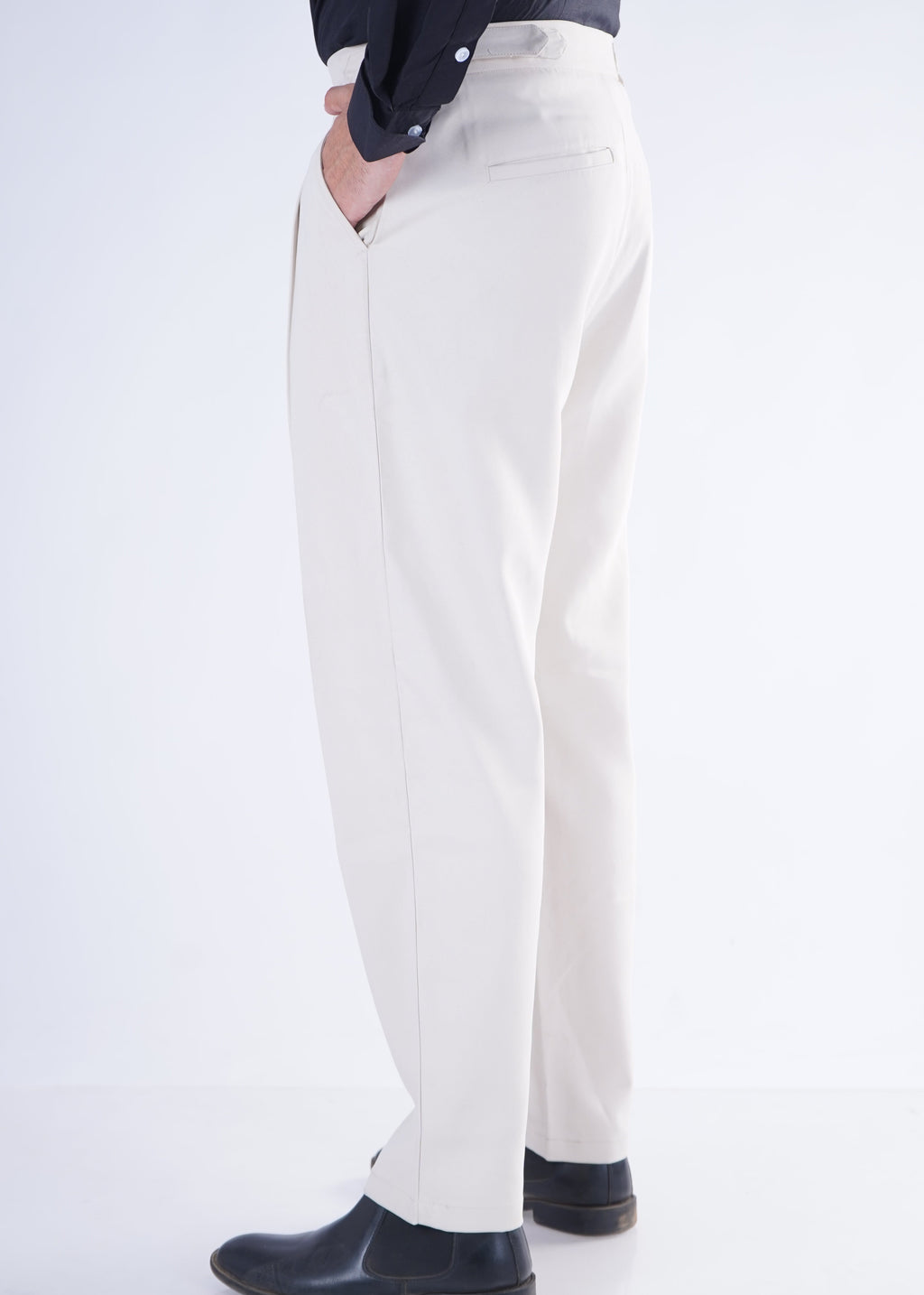 Person wearing white pants and black shoes on a white background
