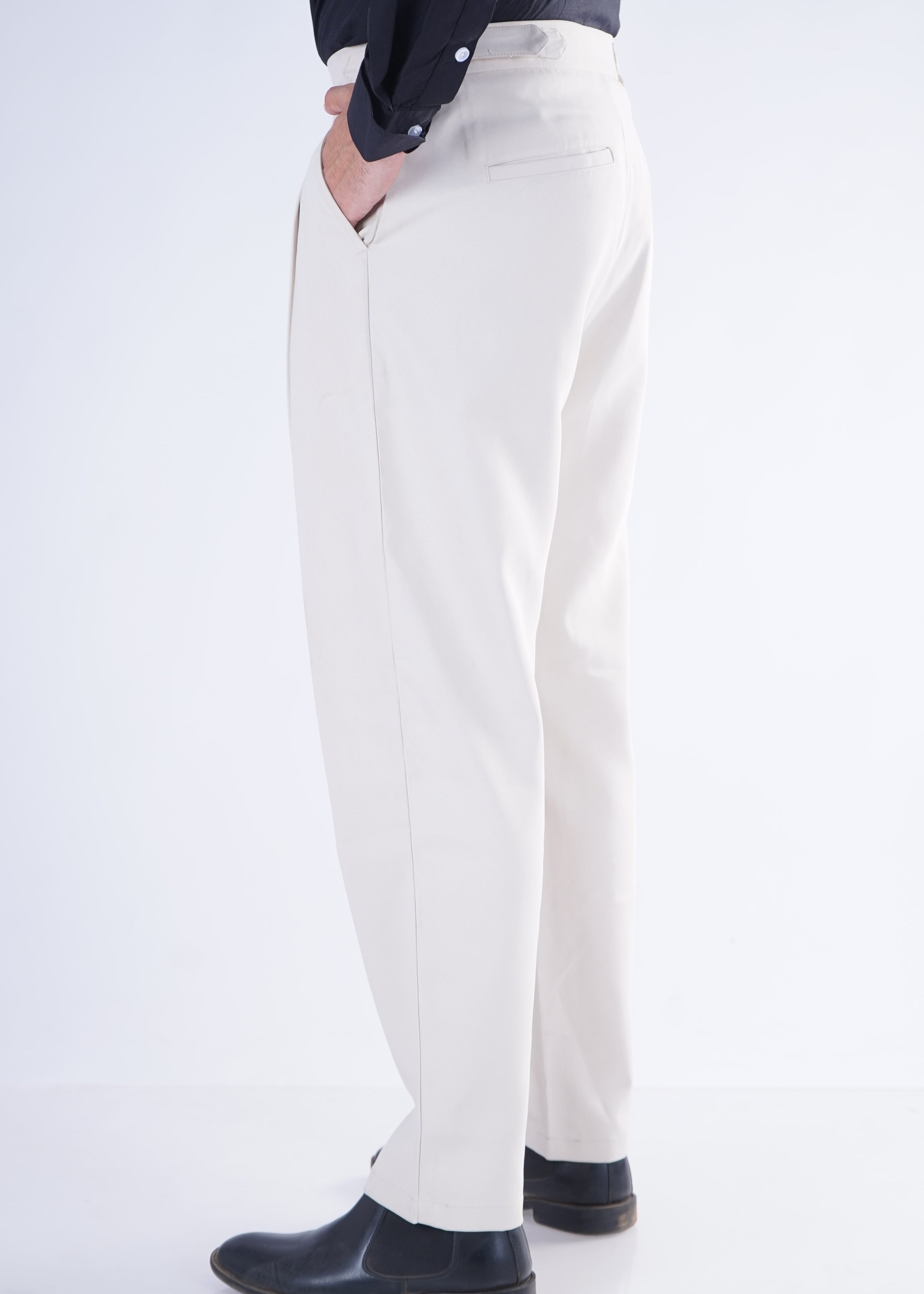 Person wearing white pants and black shoes on a white background