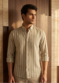 Man wearing a striped shirt standing against a wooden paneled wall