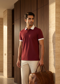 Man in a red polo shirt holding a brown leather bag in a modern interior setting