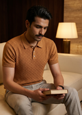 Man sitting on a couch reading a book in a cozy room with warm lighting.