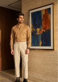 Man in a beige shirt and light pants standing in a room with a modern abstract painting on the wall.