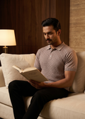 Man reading a book on a beige couch in a cozy room with warm lighting.