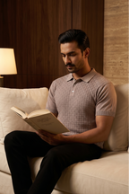 Man reading a book on a beige couch in a cozy room with warm lighting.