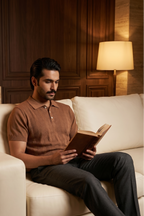 Man reading a book on a beige sofa in a warm-lit room.
