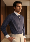 Man wearing a blue striped shirt and beige pants in a wooden interior setting