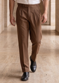 Man walking through a sunlit hallway with stone walls and floor.